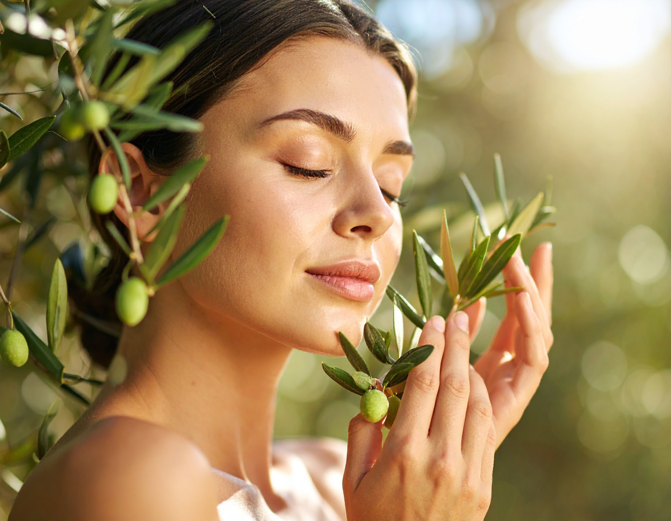 Mujer disfrutando del aroma de frutos de olivo – Inspiración para lociones con aceite de oliva – Dreams of Light Perú